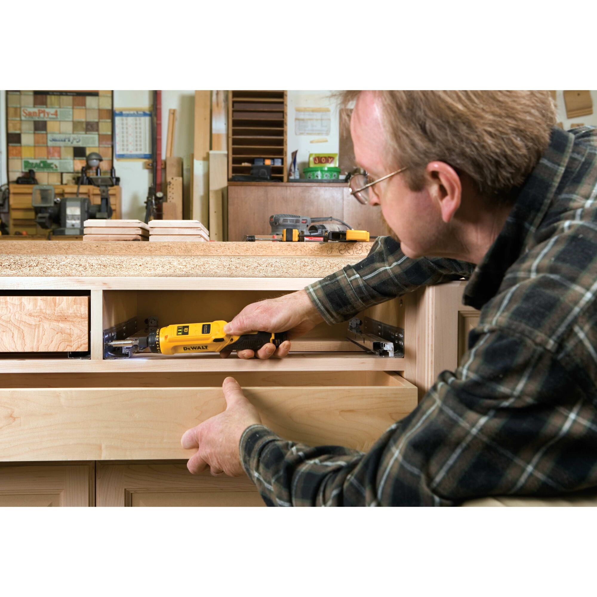 Gyroscopic screwdriver 2 battery being used by person on glide rail in wooden shelf.
