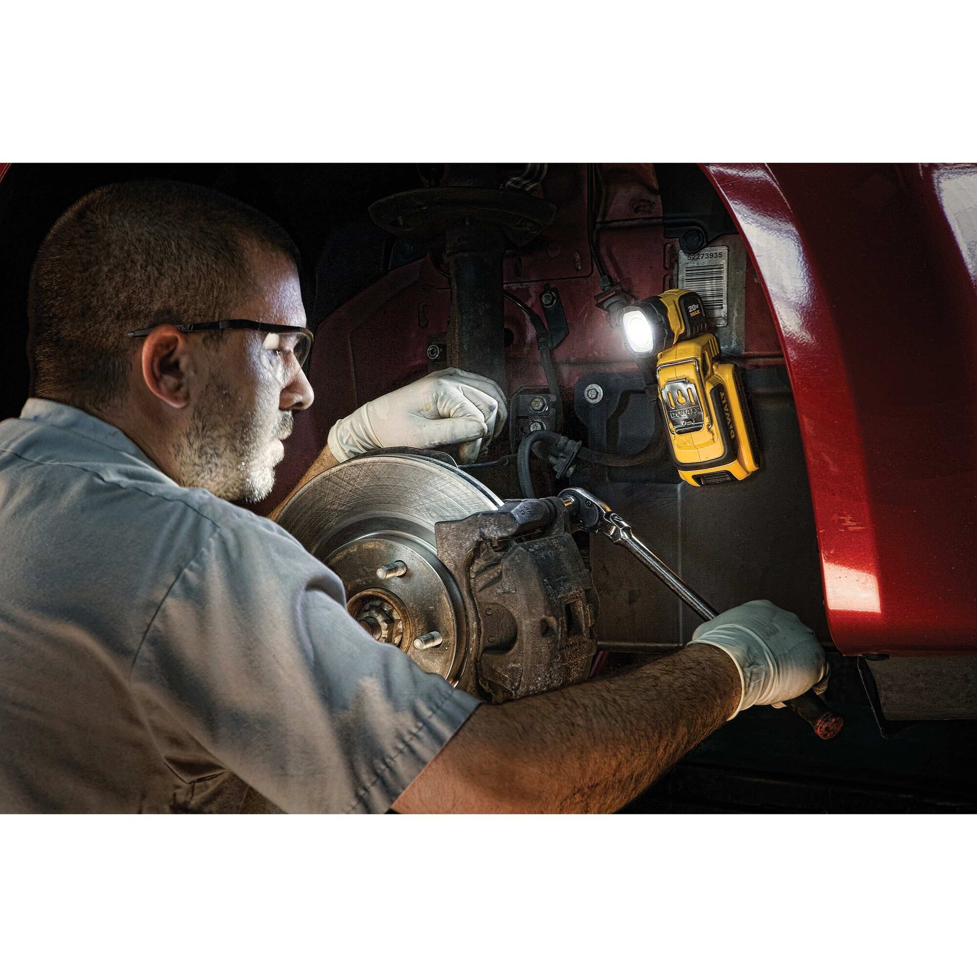 LED hand held area light being used by a person for car maintenance