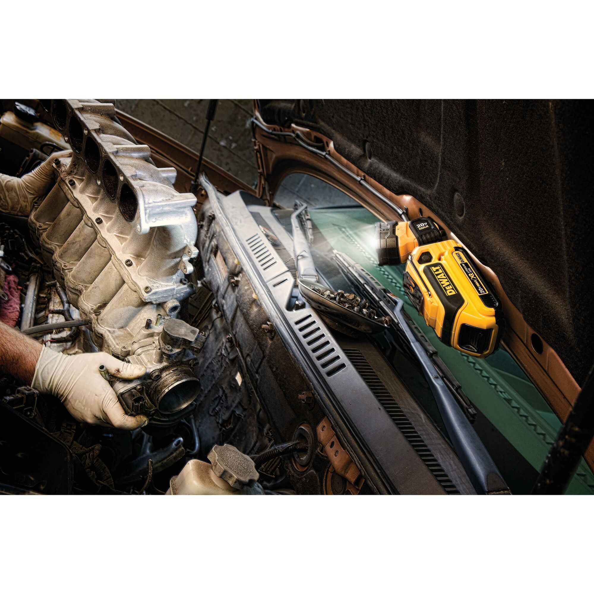 LED hand held worklight being used under a car hood to illuminate the engine